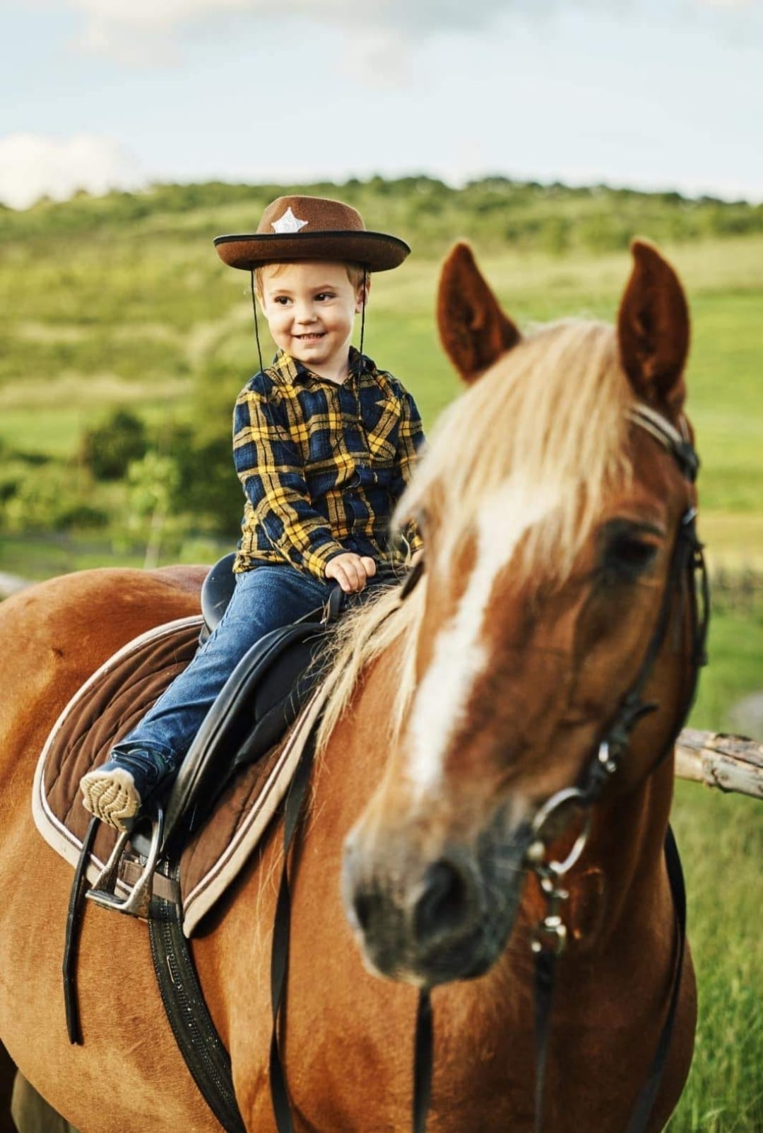 Kind mit Cowboyhut auf einem Pferd
