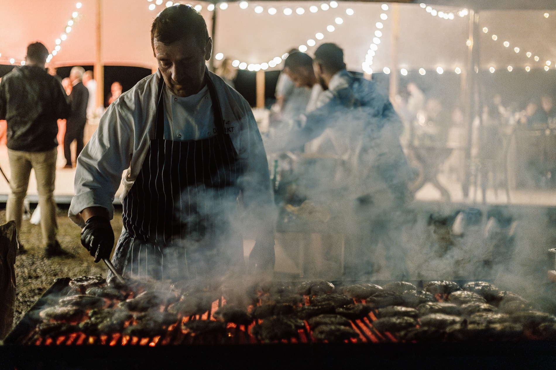 Koch am Glutgrill am Abend bei einer Veranstaltung