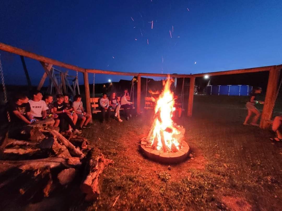 Kinder versammeln sich abends um das Lagerfeuer